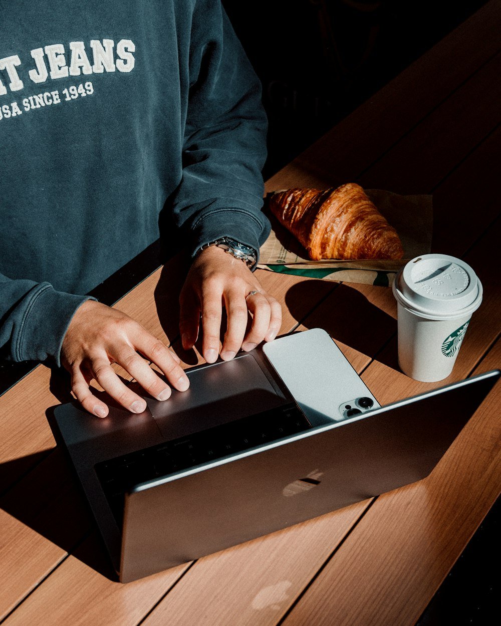 Person sitzt an einem Tisch und arbeitet konzentriert an einem Laptop
